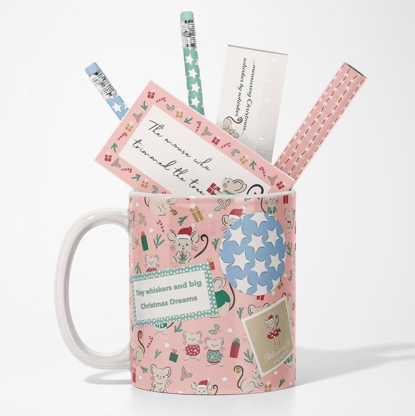 Mug mockup with a pink background, decorated with holiday-themed mice and gifts, filled with pastel pencils and stationery items.