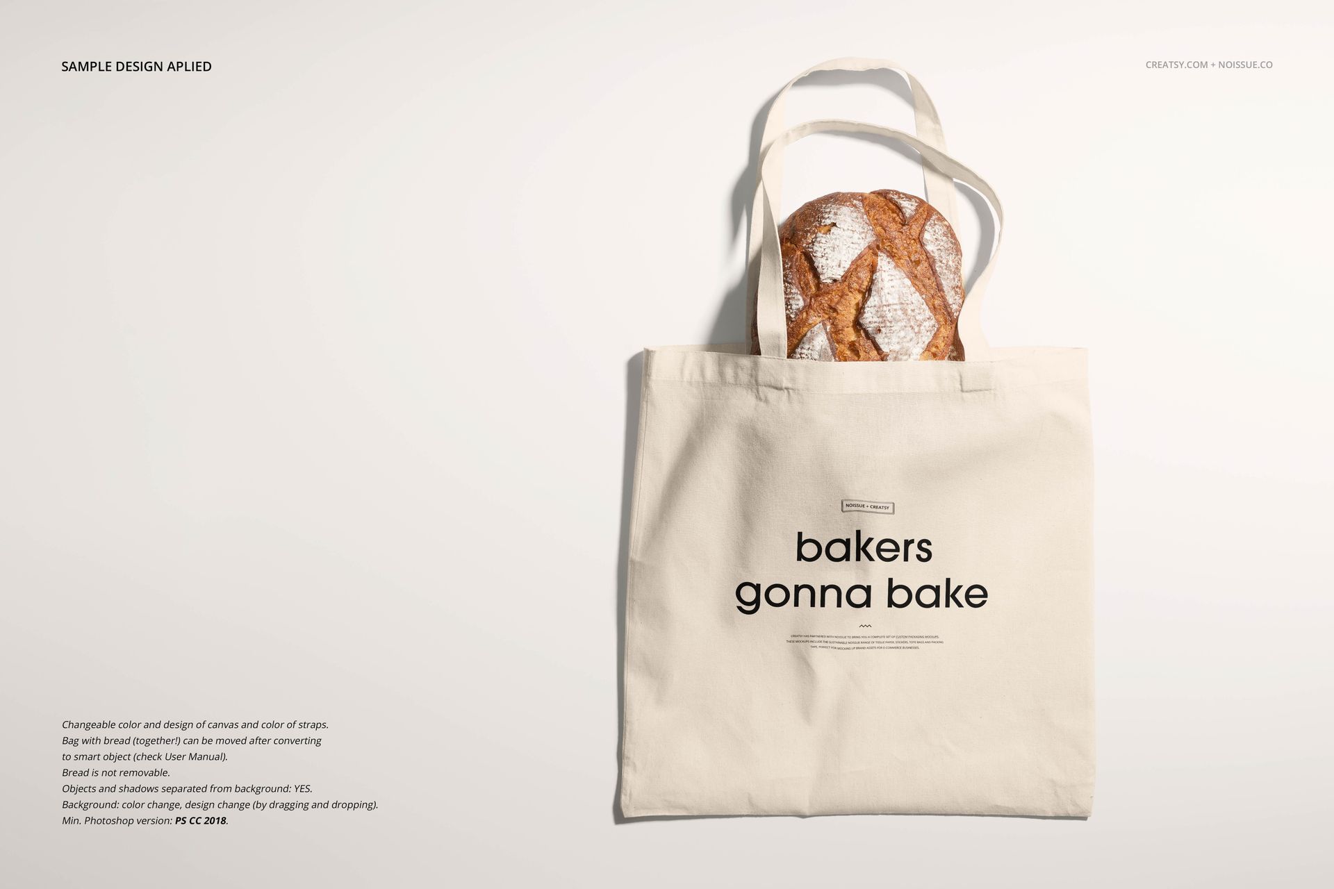 Beige fabric tote bag mockup with bold black lettering and a round loaf of bread peeking out, shown on a pale surface.