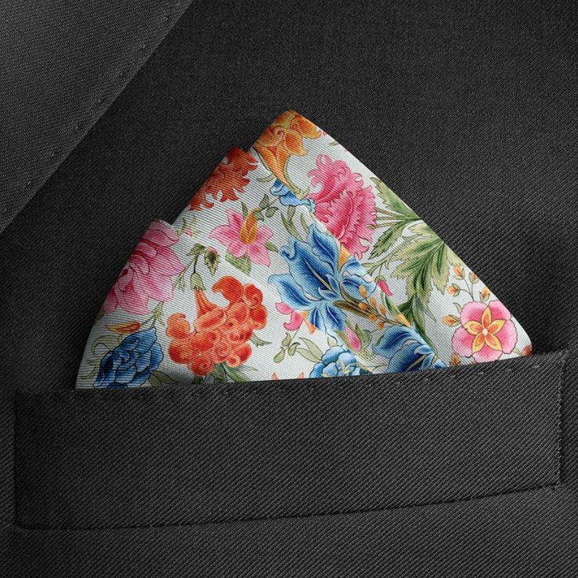 Pocket square mockup featuring a floral pattern in vibrant colors, placed in the breast pocket of a dark suit jacket.