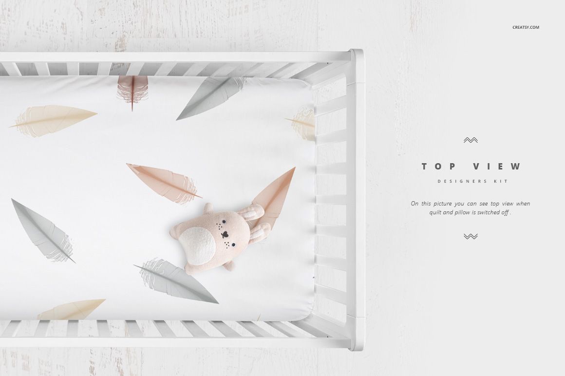 Top view of a white crib bedding mockup with pastel feather patterns and a plush bunny toy on the sheet.