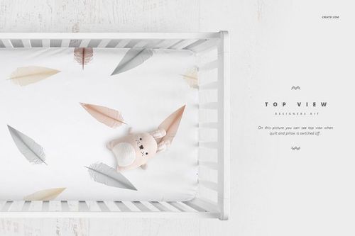 Top view of a white crib bedding mockup with pastel feather patterns and a plush bunny toy on the sheet.