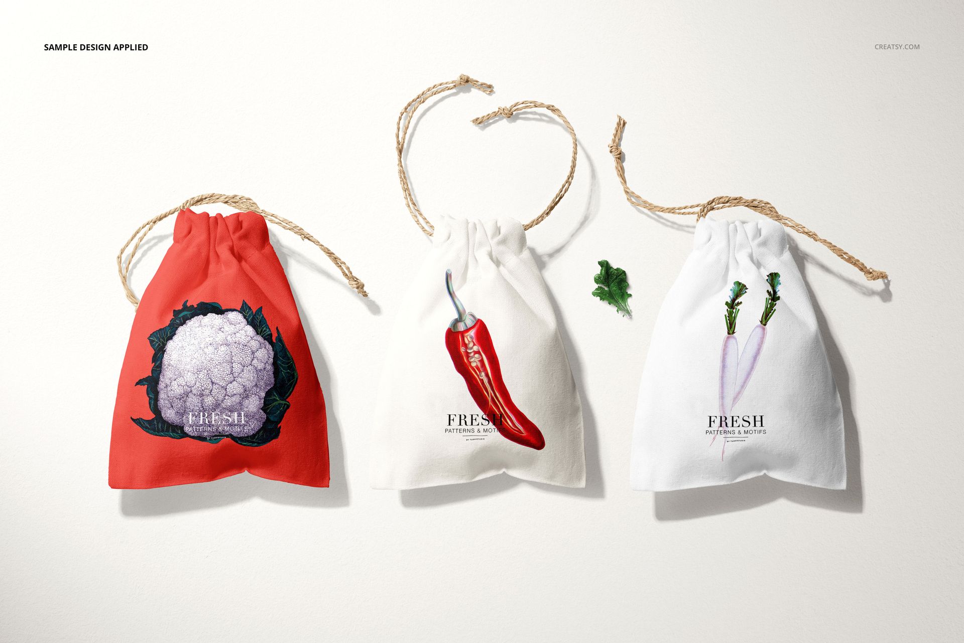 Linen drawstring pouch PSD mockup set with three bags in red, off-white, and white, each with a unique vegetable print.