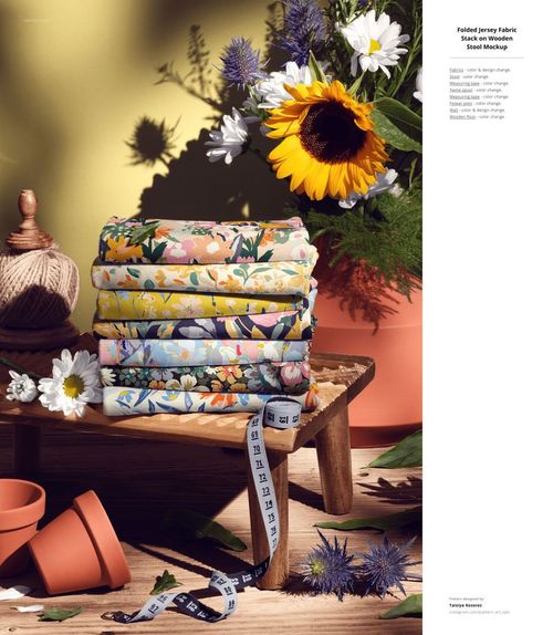 Folded jersey fabric mockup featuring vibrant floral designs, tape measure, and potted flowers in a sunlit scene.