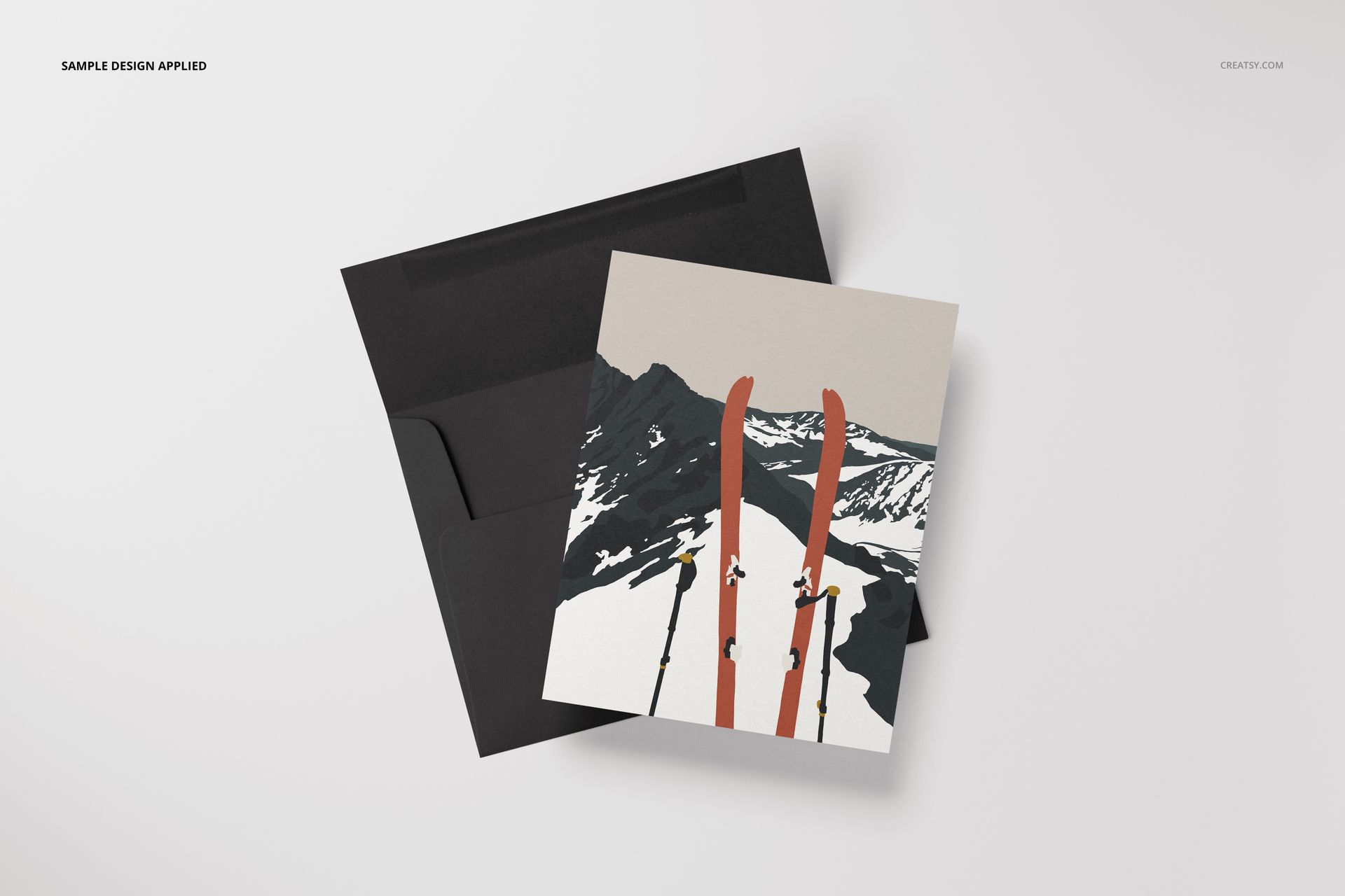 A2 card mockup with a mountain and ski design, paired with a black envelope, shown from a top view on white background.