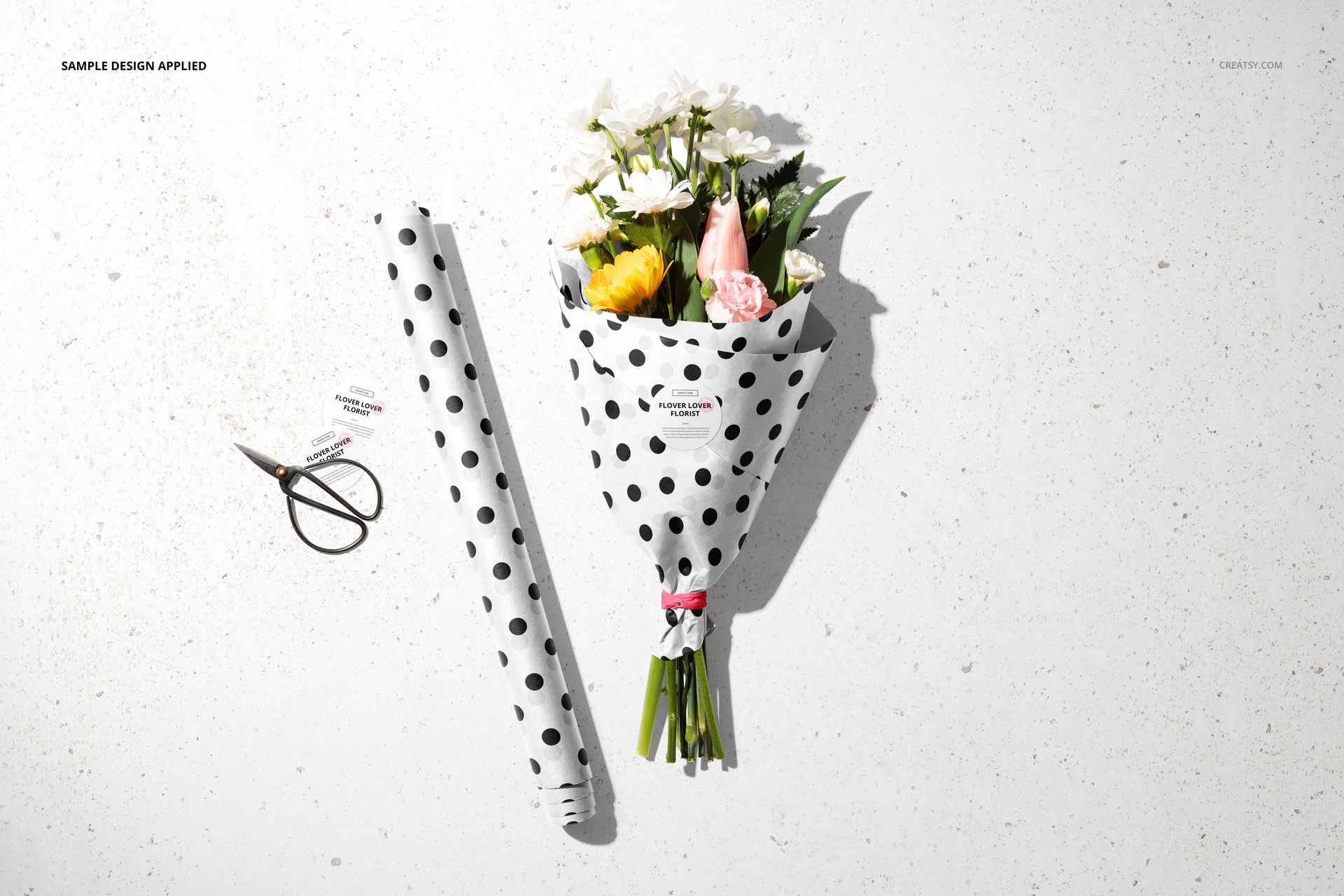 Flowers Packaging Mockup Set showing a wrapped bouquet, polka dot paper roll, and scissors arranged on a bright surface.