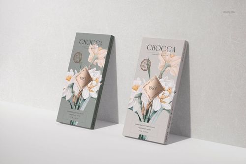Two chocolate bar packaging mockups with floral designs, standing upright on a light textured surface in a front view.