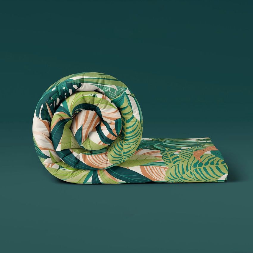 Microfiber comforter mockup featuring a rolled blanket with a lush green and beige tropical leaf pattern on a dark green background.