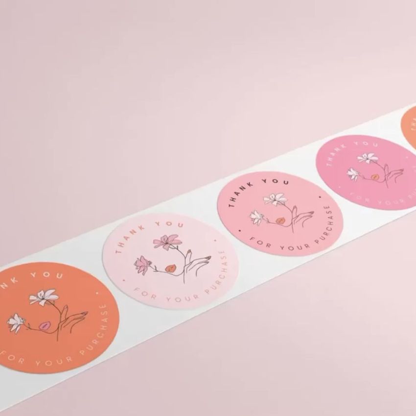 Sticker mockup showing a row of round stickers with floral illustrations and thank you text on a soft pink background.