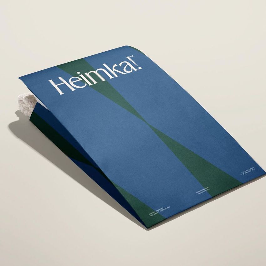 Kraft mailer mockup featuring a blue and green geometric design, photographed on a light surface with a towel peeking out.