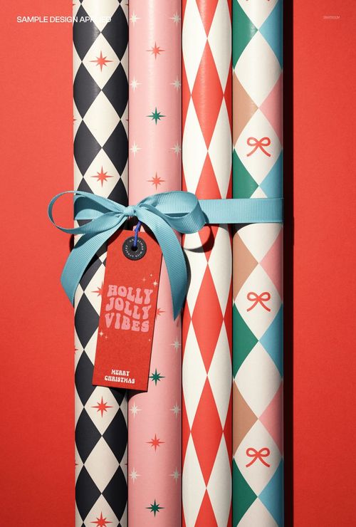 PSD mockup featuring four colorful wrapping paper rolls with diamond and star designs, blue ribbon, and paper label.