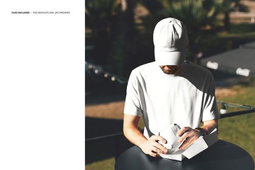 Person in a white t-shirt and cap unwrapping a burger package while seated outside, mockup scene in daylight.
