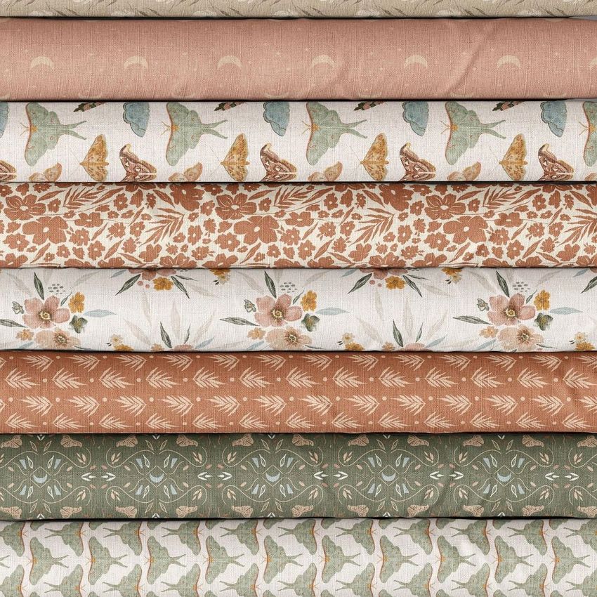Folded fabrics mockup showing a stack of patterned textiles in earthy tones with floral, bird, and geometric designs.