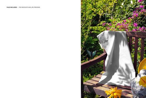 PSD mockup showing a plain fabric hanging on a garden bench surrounded by lush plants and colorful blossoms.