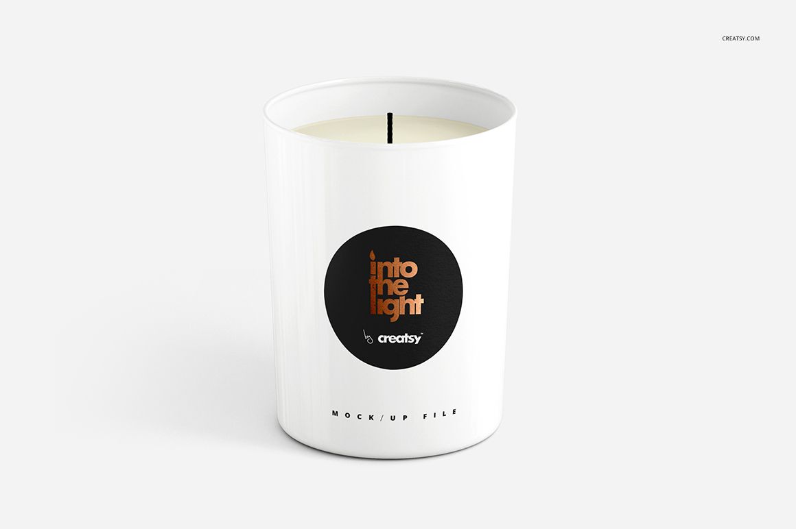 White cylindrical candle mockup with a black round label and centered wick, displayed against a plain backdrop.