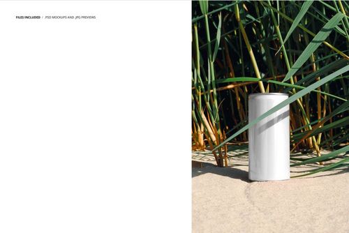 Plain white 200ml can standing upright on sandy ground beside tall green riparian grass, front view mockup.
