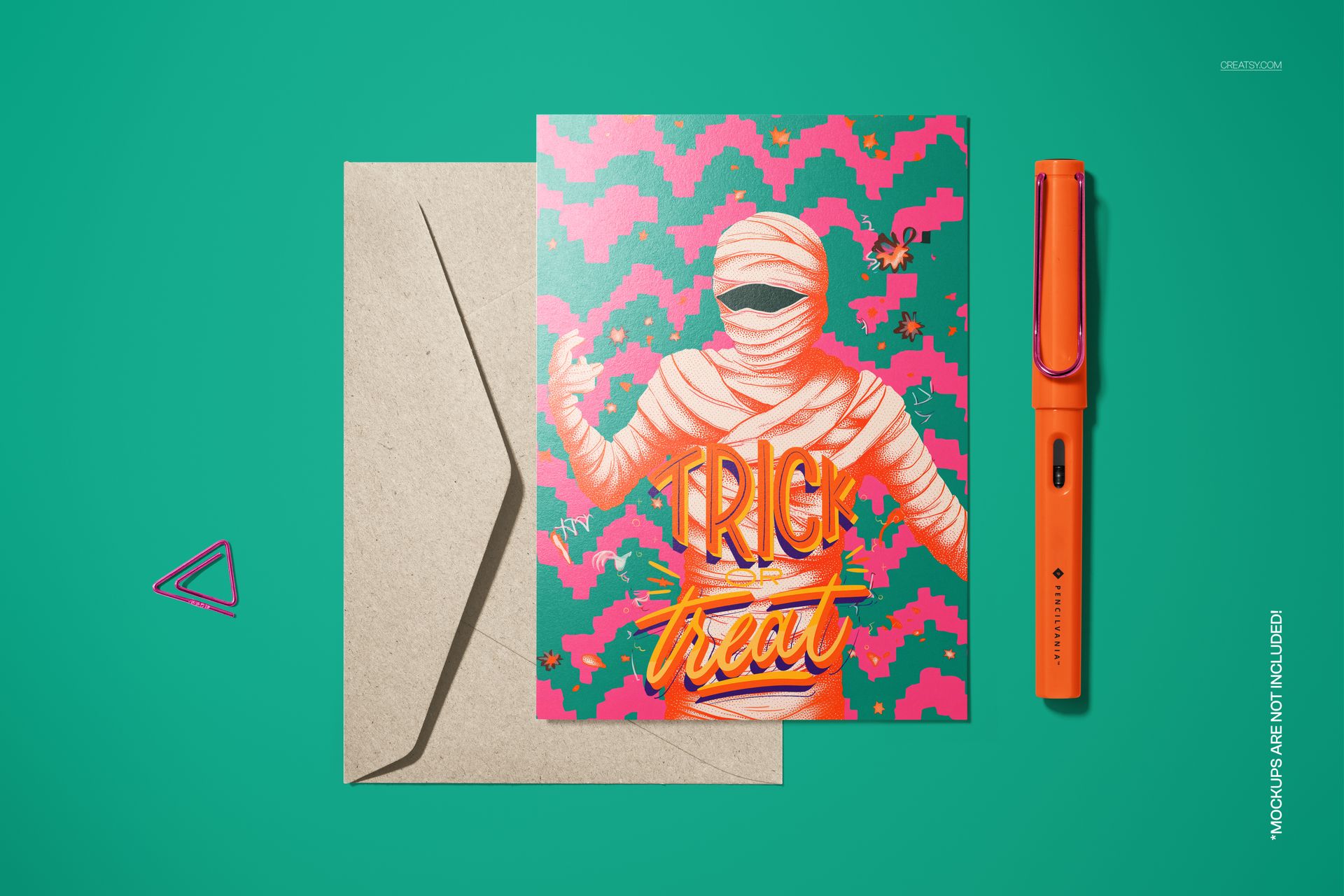 Halloween 5x7 card mockup with a creepy mummy design, kraft envelope, and orange pen on a green surface.