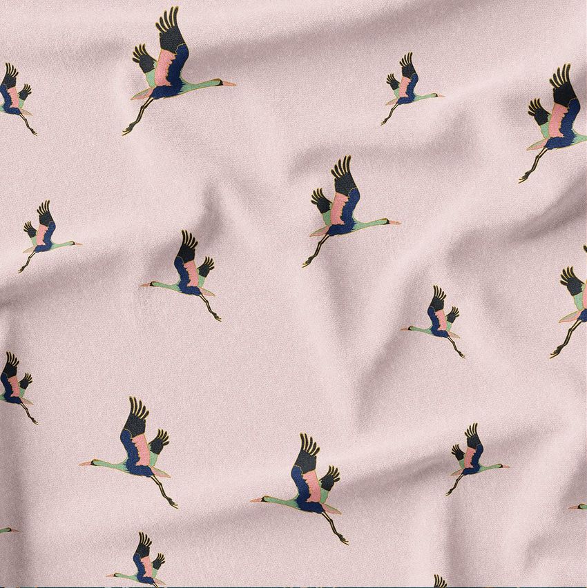 Creased fabric mockup featuring a repeating pattern of stylized cranes in flight on a light pink background.
