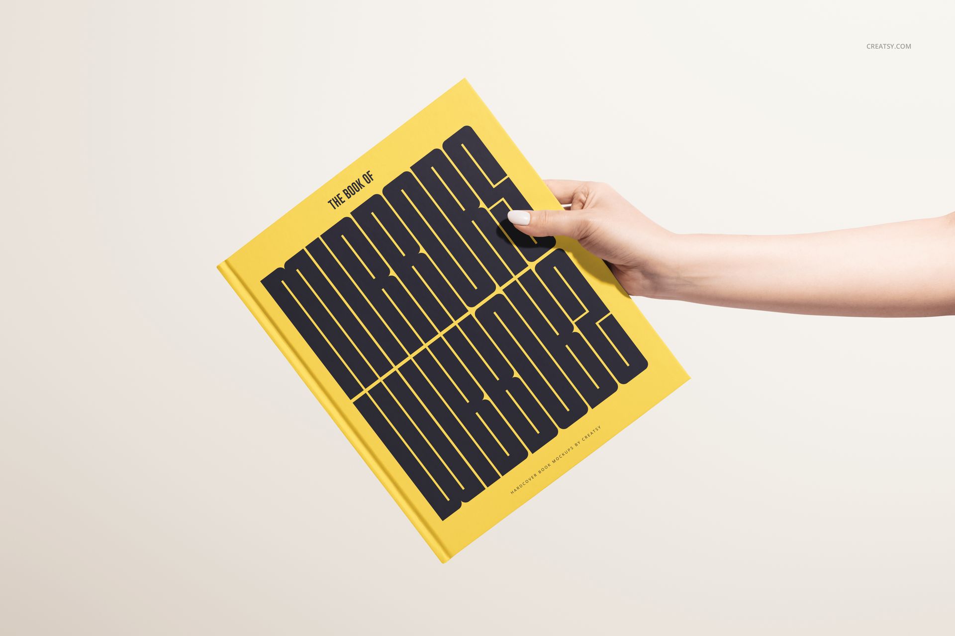 Yellow hardcover book mockup featuring large black lettering, held by a hand with a neutral background.