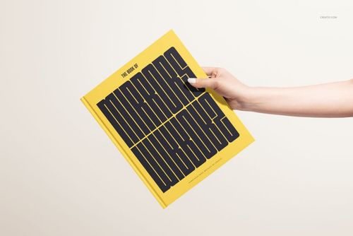 Yellow hardcover book mockup featuring large black lettering, held by a hand with a neutral background.