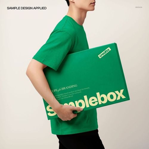 Man in a green shirt holding a large rectangular packaging box with bold yellow text, front view mockup.