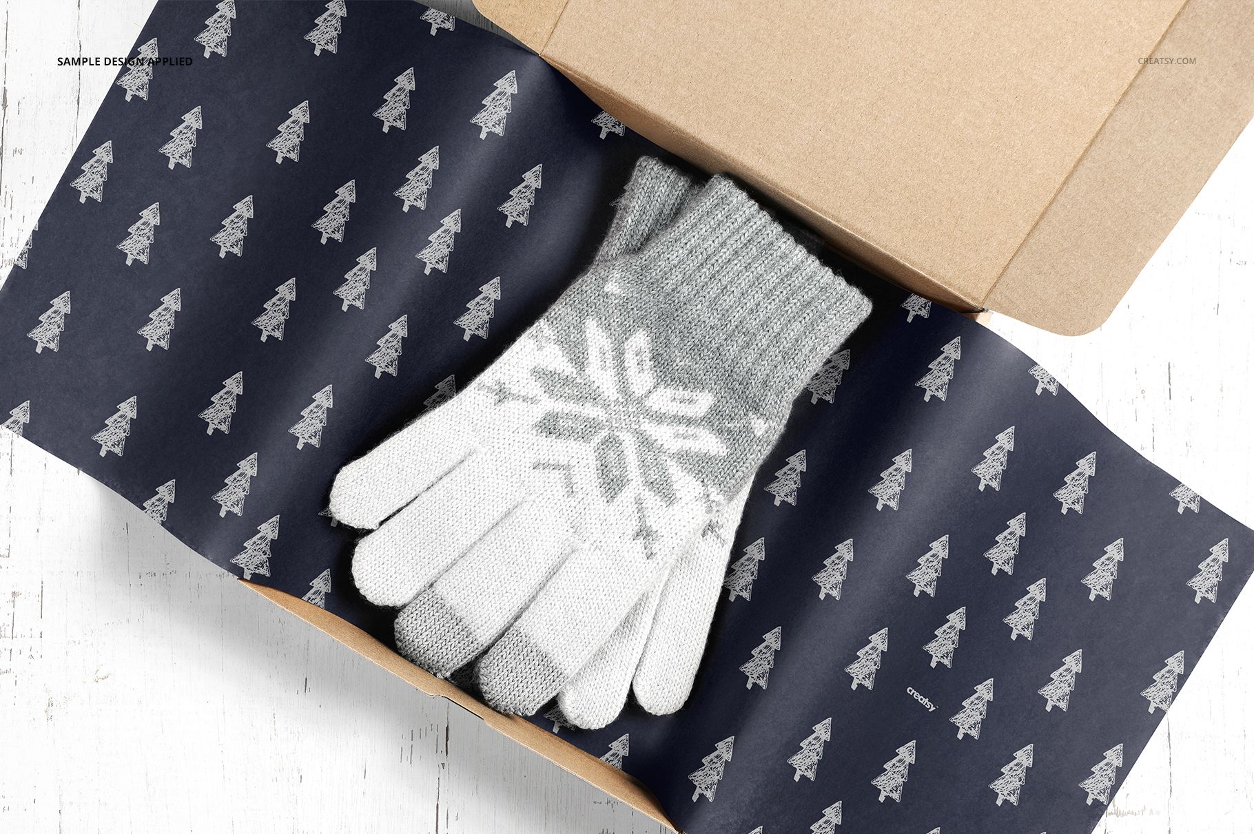 Mailer box mockup with patterned tissue paper and gray knit gloves, displayed from a top-down perspective on a white background.