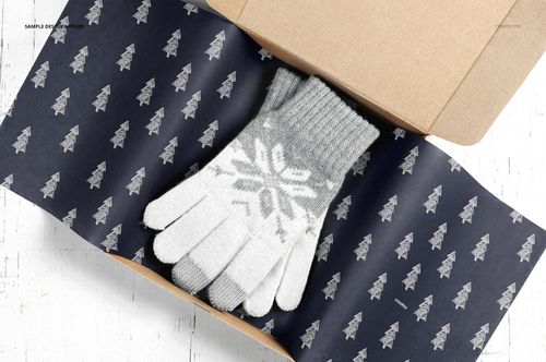 Mailer box mockup with patterned tissue paper and gray knit gloves, displayed from a top-down perspective on a white background.