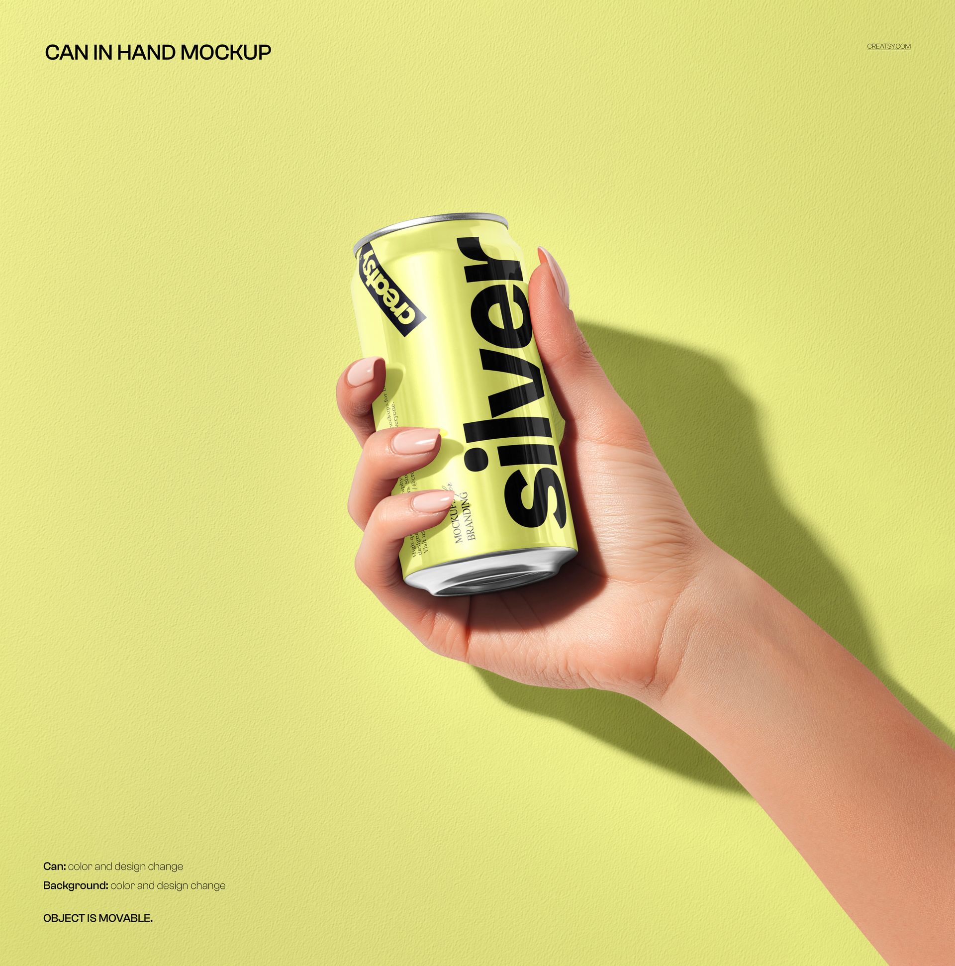 Hand holding a silver and yellow soda can against a light yellow textured background, front view mockup.