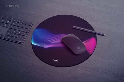 Gaming mouse pad mockup featuring a circular shape and vibrant gradient design, placed beside a keyboard and pen.
