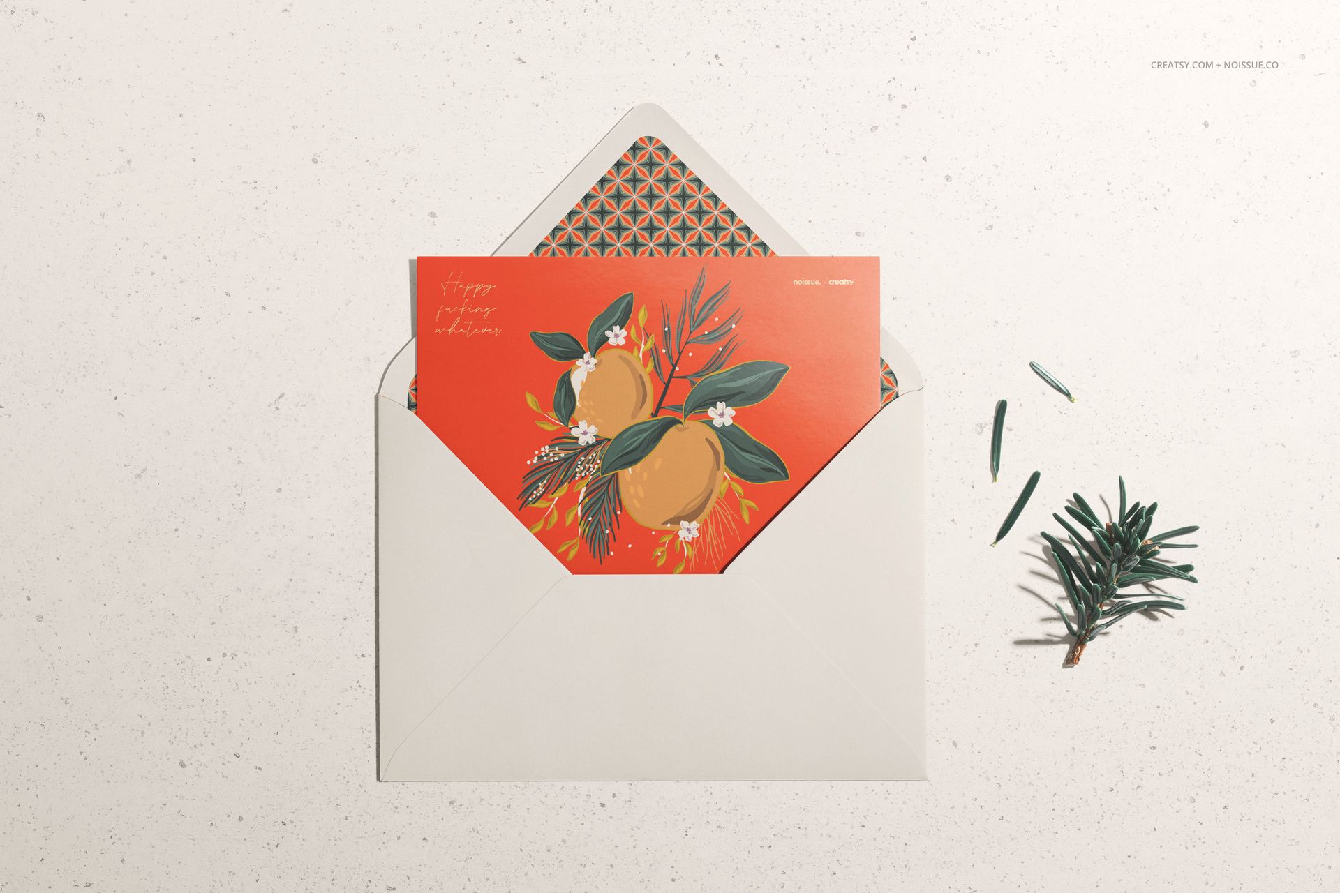 PSD mockup featuring a decorative card with fruit and foliage design in a white envelope, flat lay with scattered greenery.