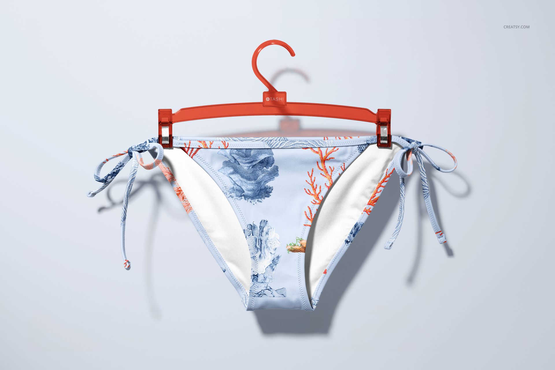 Bikini bottom mockup featuring sea life illustrations and coral motifs in blue and orange, hanging on a plastic hanger.