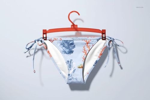 Bikini bottom mockup featuring sea life illustrations and coral motifs in blue and orange, hanging on a plastic hanger.