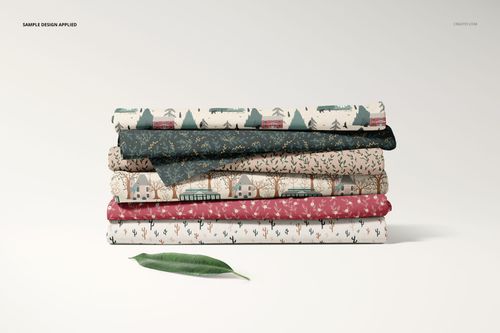 Front view of a fabric stack mockup showing assorted folded fabrics with botanical and geometric designs, leaf accent included.