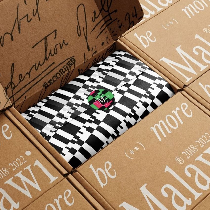Mailing box mockup with open flaps revealing black and white patterned tissue paper inside, viewed from above.