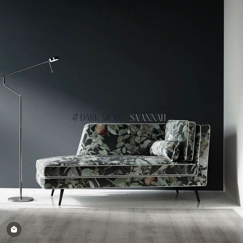Chaise lounge sofa mockup with dark floral upholstery set against a matte black wall, accompanied by a modern floor lamp.