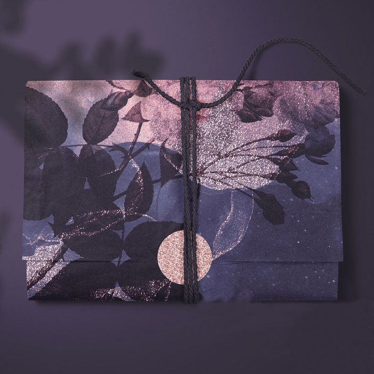 Tissue paper mockup featuring a folded sheet with a dark floral pattern, tied with black string on a purple background.