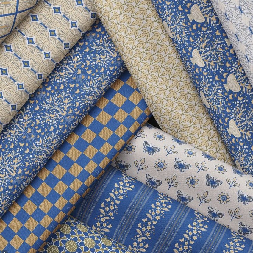 Folded fabrics mockup featuring multiple textile pieces arranged diagonally, displaying blue and beige floral and geometric patterns.