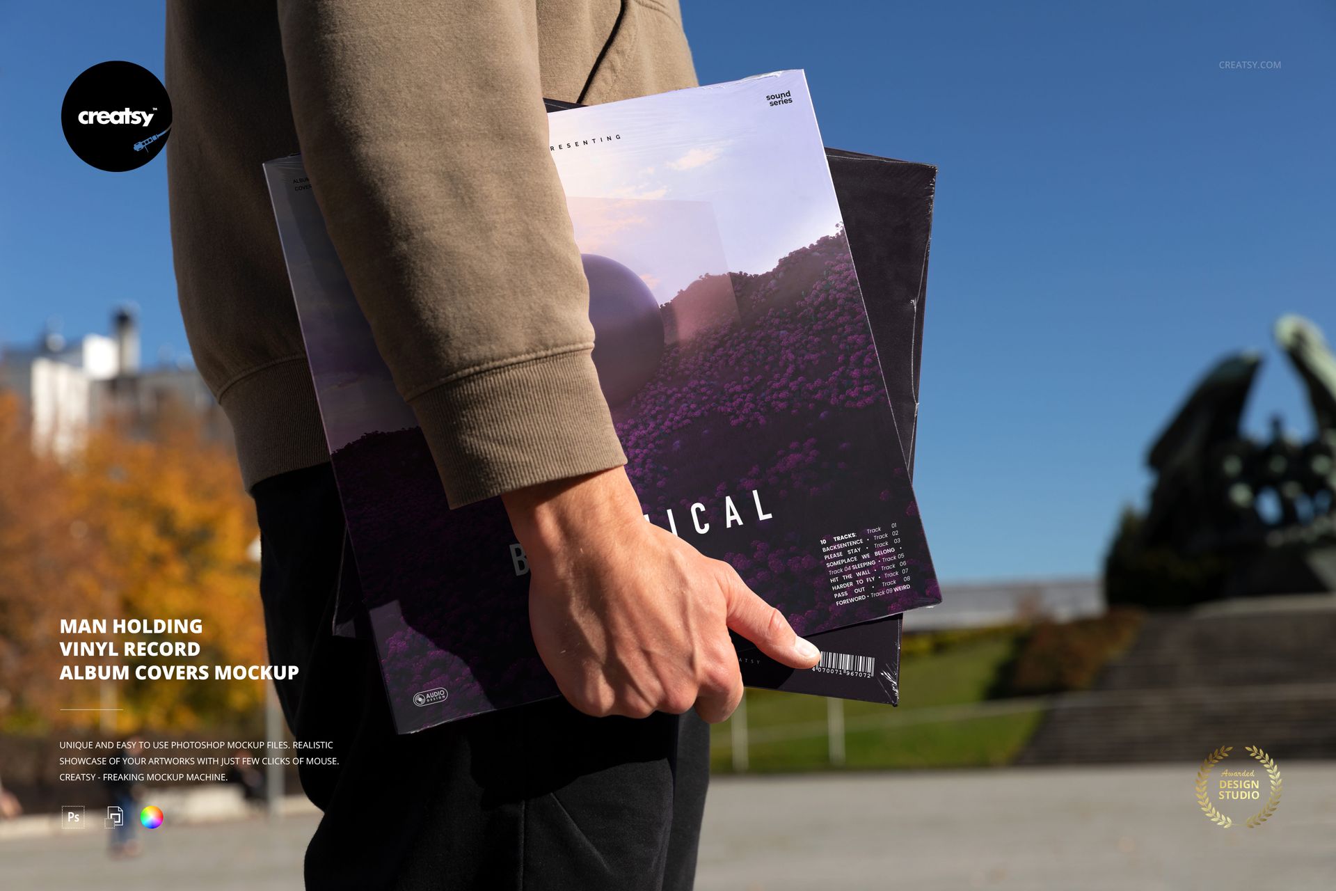 Outdoor scene showing a man’s arm and hand holding vinyl record album covers, mockup for music-themed PSD presentations.
