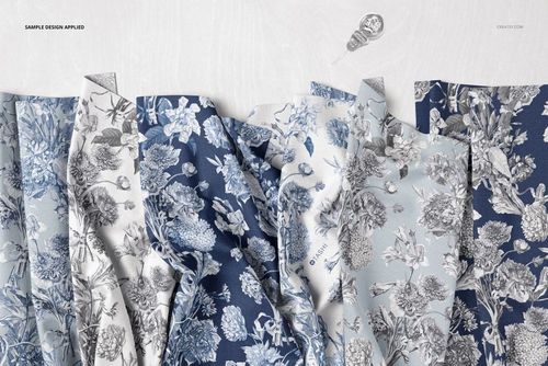 PSD mockup showing multiple folded fabric samples with detailed botanical prints in cool colors, viewed from above.