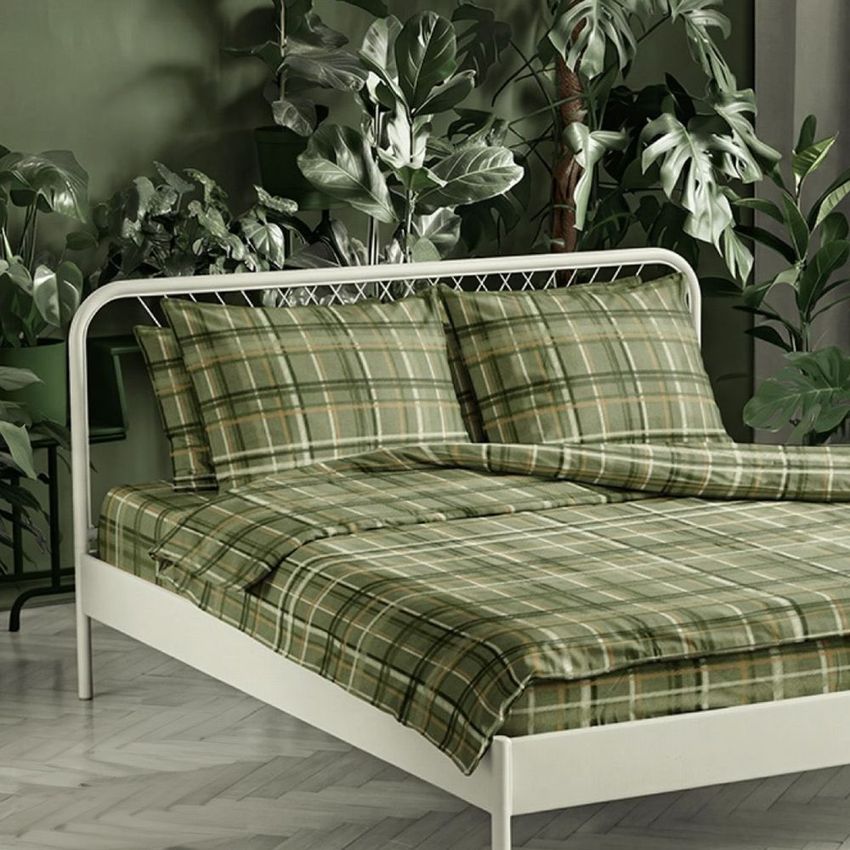 Bedding set mockup featuring green plaid sheets and pillows on a white bed frame, surrounded by lush indoor plants.