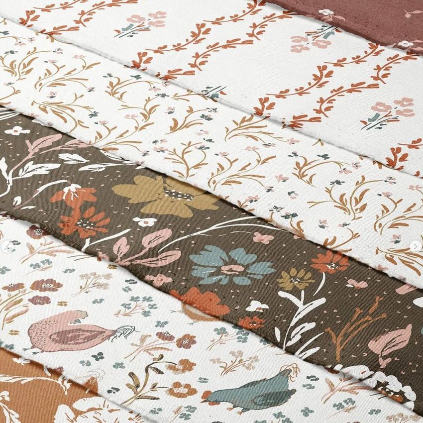 Fanned cotton fabric stack mockup featuring multiple layers of patterned textiles in earthy tones, viewed from above.