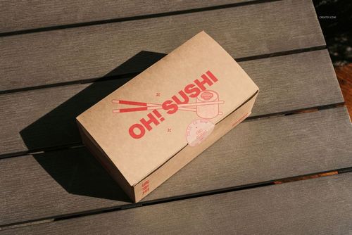 Rectangular takeaway box mockup on a wooden outdoor table, featuring brown kraft paper and red sushi-themed print.