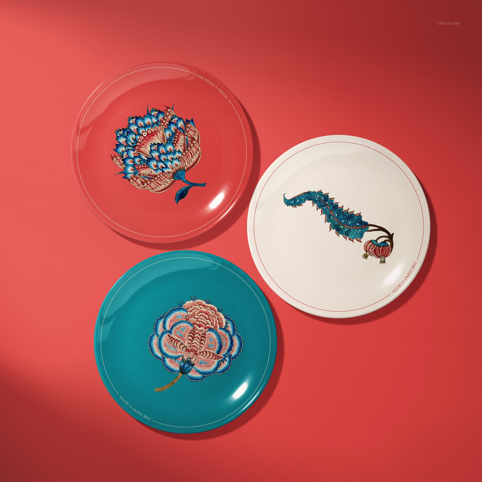 Ceramic plates mockup featuring intricate blue, pink, and green patterns, displayed against a red surface.