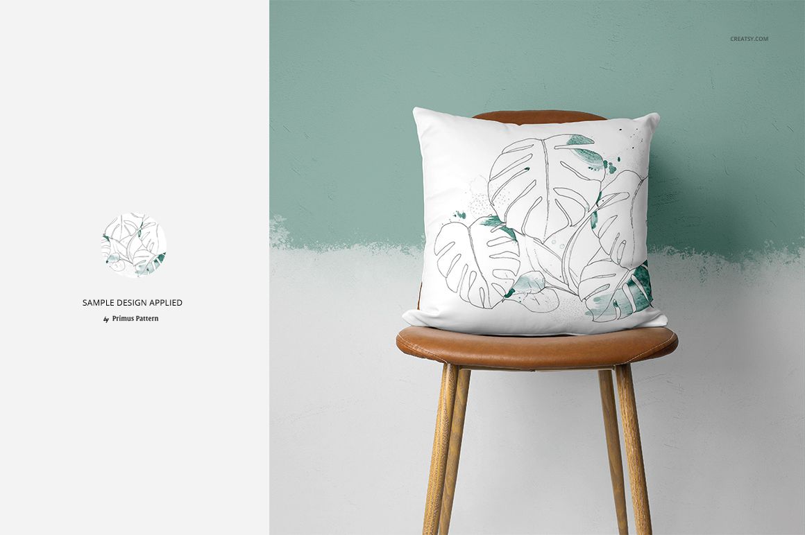 Mockup of a white pillow featuring a botanical leaf design, displayed on a tan chair in a modern interior.