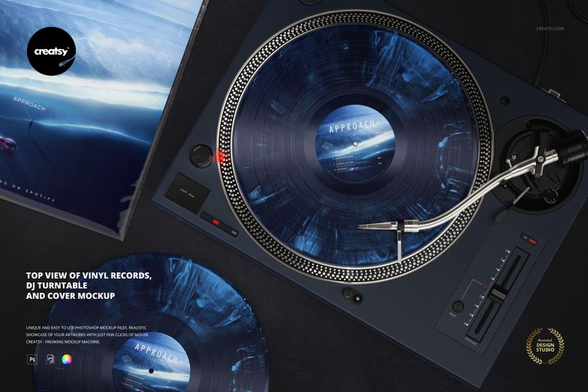 Top view of a DJ turntable with a blue vinyl record, matching record cover, and a second vinyl on a black surface.