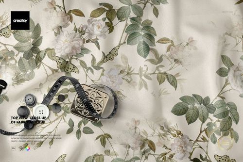 Top view of a fabric mockup displaying a botanical print with white roses, green leaves, and butterflies on a cream surface.