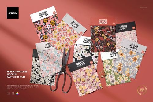 Assorted fabric swatches with floral patterns arranged on a pink surface, accompanied by a pair of scissors.