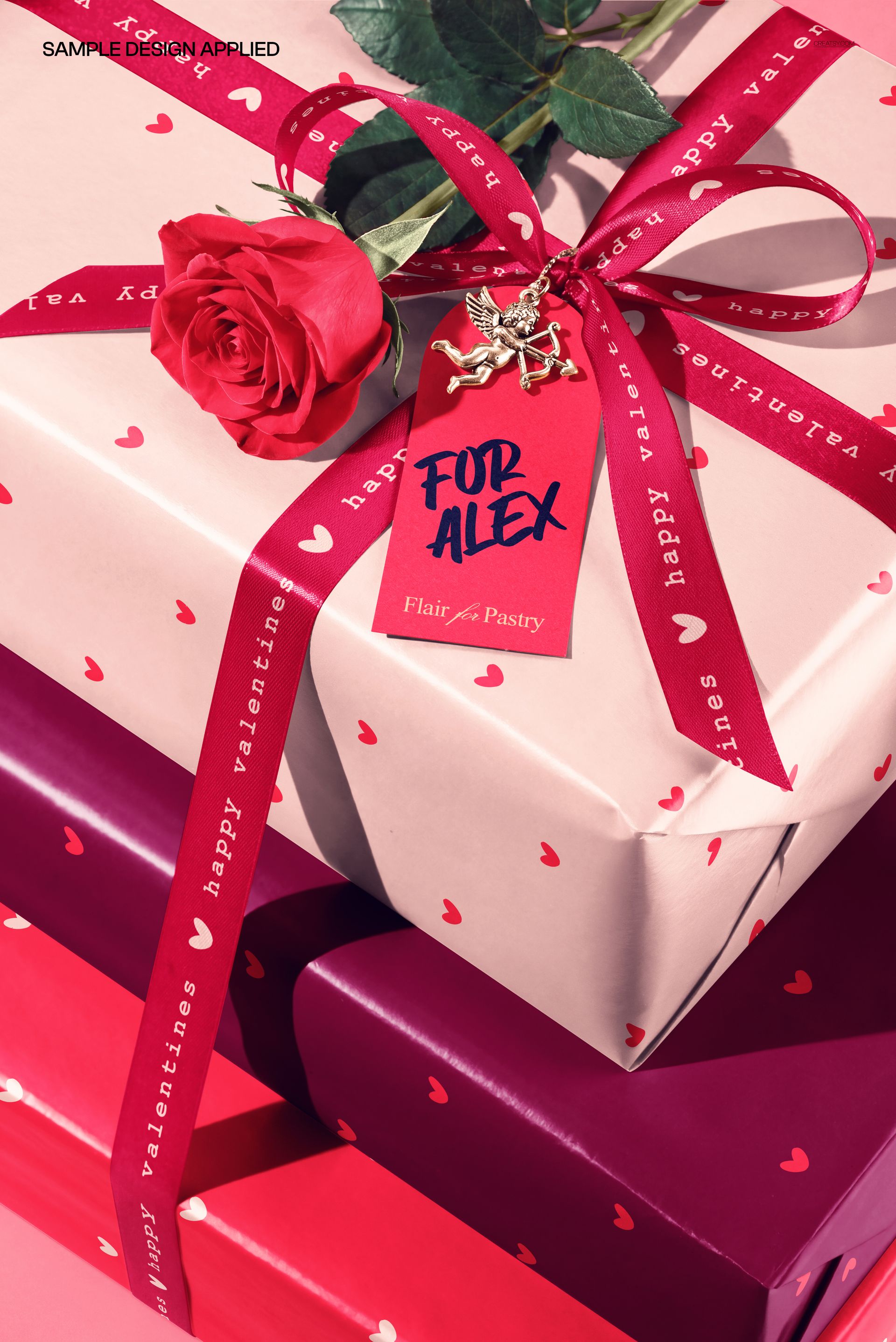 Valentine-themed packaging mockup showing layered gift boxes with heart motifs, ribbon, and a rose accent.