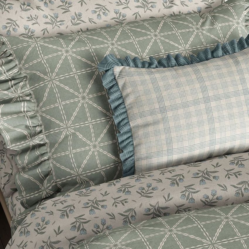 Ruffled pillow and duvet cover mockup featuring green geometric and floral patterns with blue plaid accents on a bed.