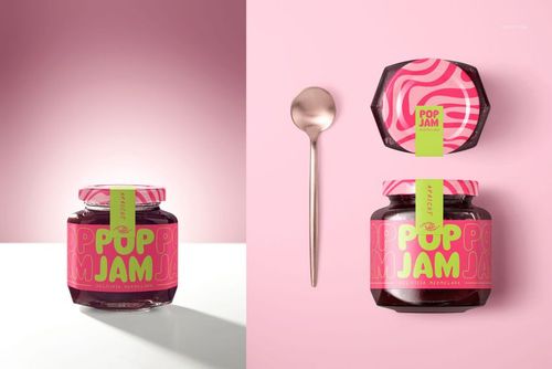 PSD mockup of a blackberry jam jar featuring a bold pink and green design, displayed next to a spoon on a split pink surface.