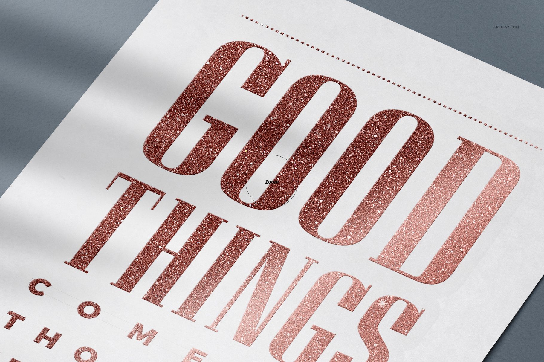 Close-up of a decals stickers mockup featuring metallic rose gold text on a white rectangular sheet, angled on a gray surface.
